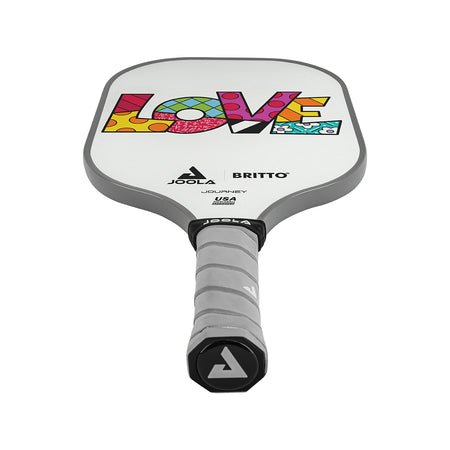 White Background Image: JOOLA x BRITTO paddle, grey handle, white paddle face with LOVE written in colorful BRITTO art style.