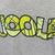 White Background Image: Close up of Heather grey BRITTO x JOOLA shirt with large yellow BRITTO x JOOLA logo.