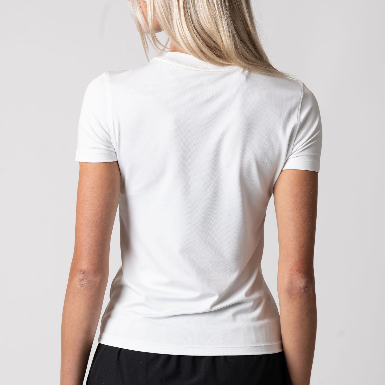 Image showing the back of a female model who is wearing the JOOLA Women's Club Short Sleeve Shirt, White.